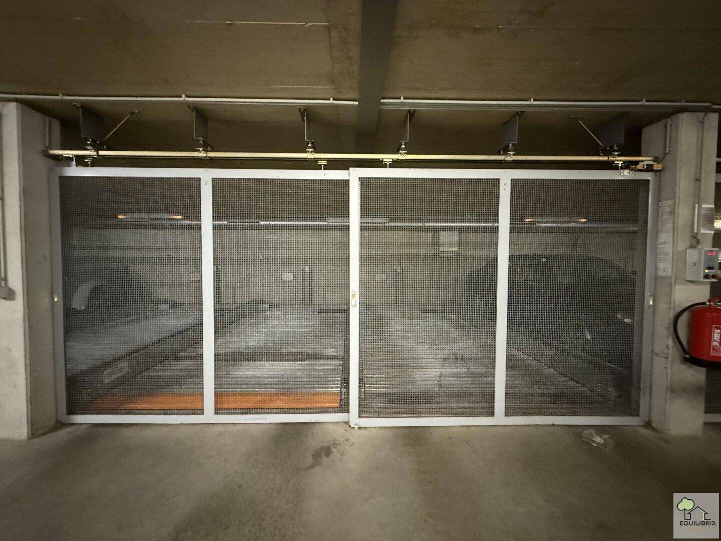 Doppelparker-System in der Tiefgarage mit Gittertüren für zwei Fahrzeuge und Brandschutzvorrichtung.