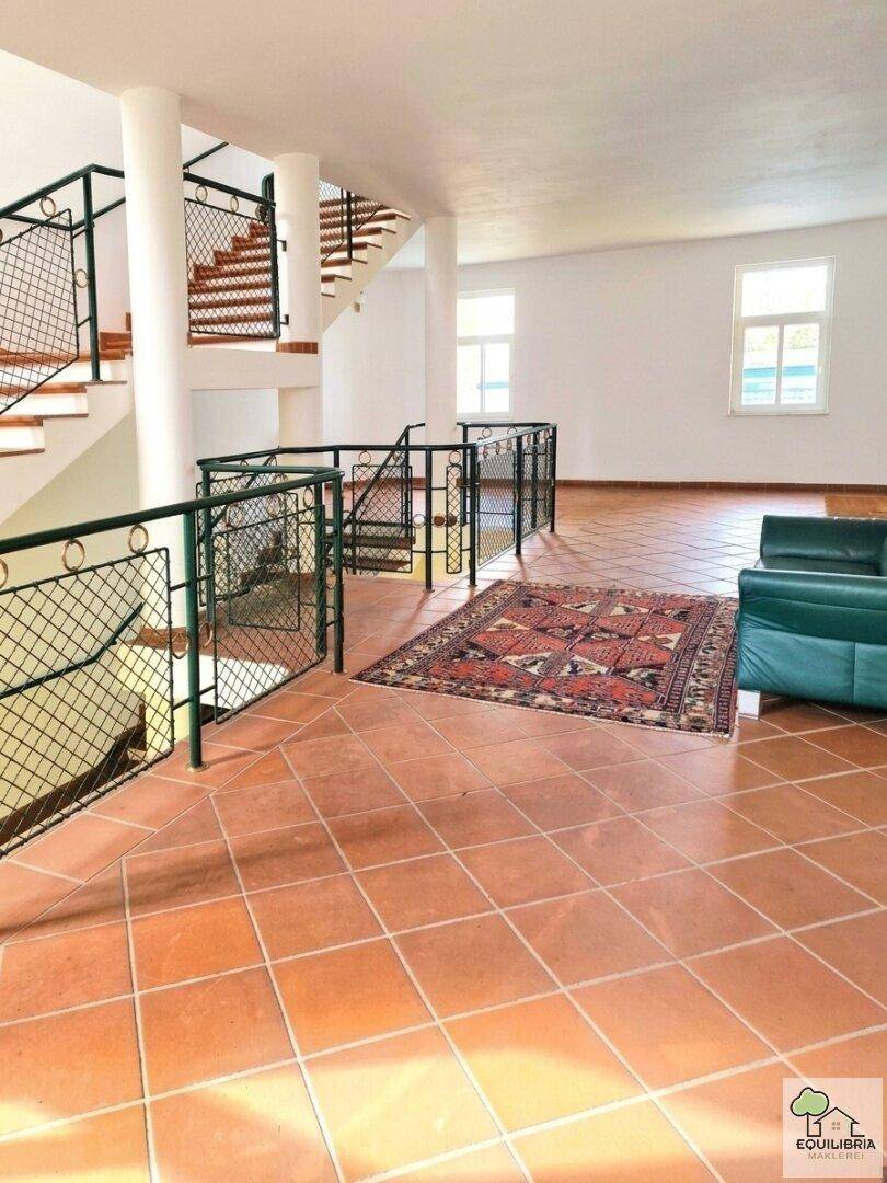 Heller Eingangsbereich mit Terrakottafliesen, einer breiten Treppe und dekorativen Pflanzen.