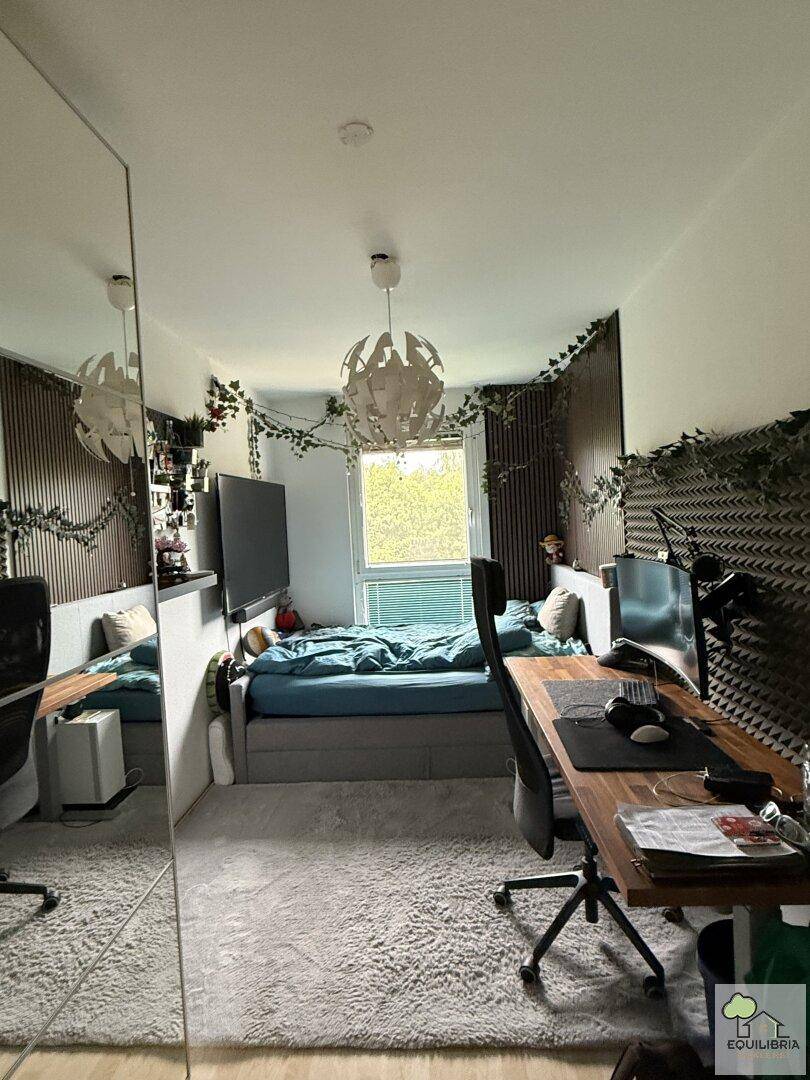 Modernes Schlafzimmer mit integriertem Arbeitsbereich, großem Fenster und dekorativen Pflanzenranken.
