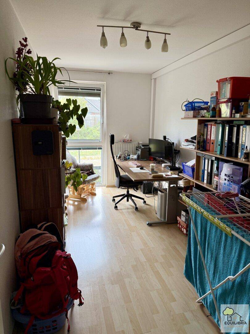 Funktionales Arbeitszimmer mit Schreibtisch, Regalen und einem Fenster, das viel Tageslicht hereinlässt.