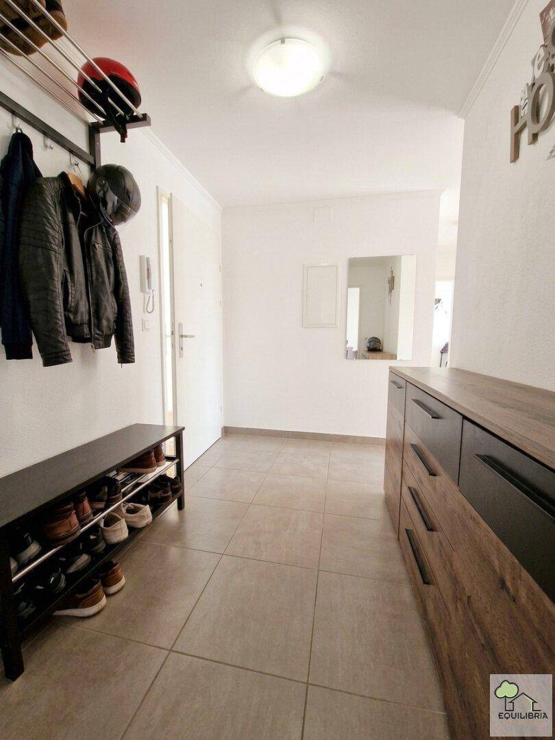 Geräumiger Flur mit Fliesenboden, Garderobe und praktischer Kommode im Eingangsbereich.