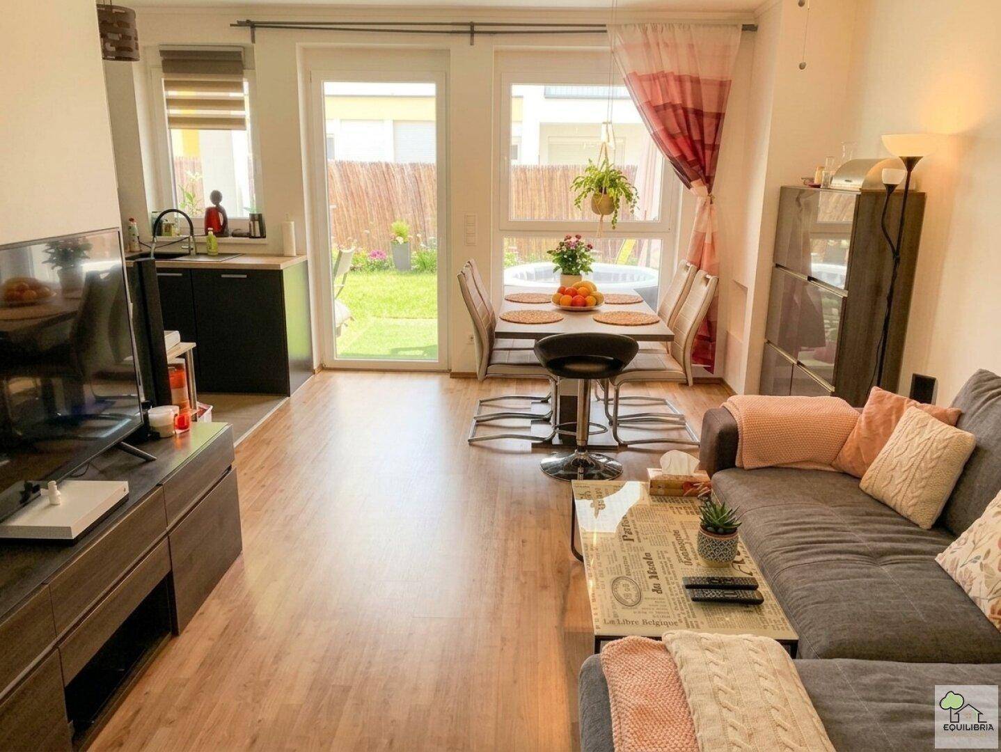 Heller Wohn- und Essbereich mit Laminatboden, Zugang zum Garten und moderner Einrichtung.