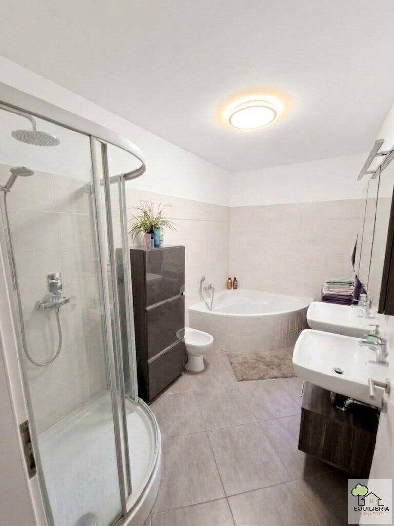 Großes Badezimmer mit Eckbadewanne, Dusche, Doppelwaschbecken und modernen Fliesen.