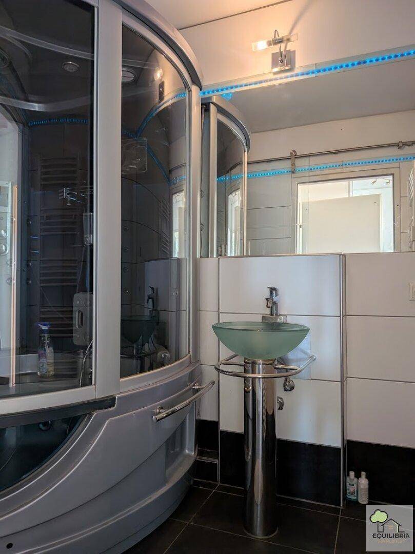 Modernes Badezimmer mit runder Duschkabine, Glaswaschbecken und dunklen Fliesen.
