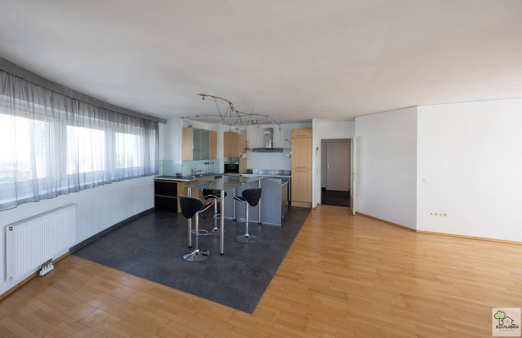 Moderne Einbauküche mit Holzschränken, Edelstahlfronten und Bartresen im offenen Wohnbereich.