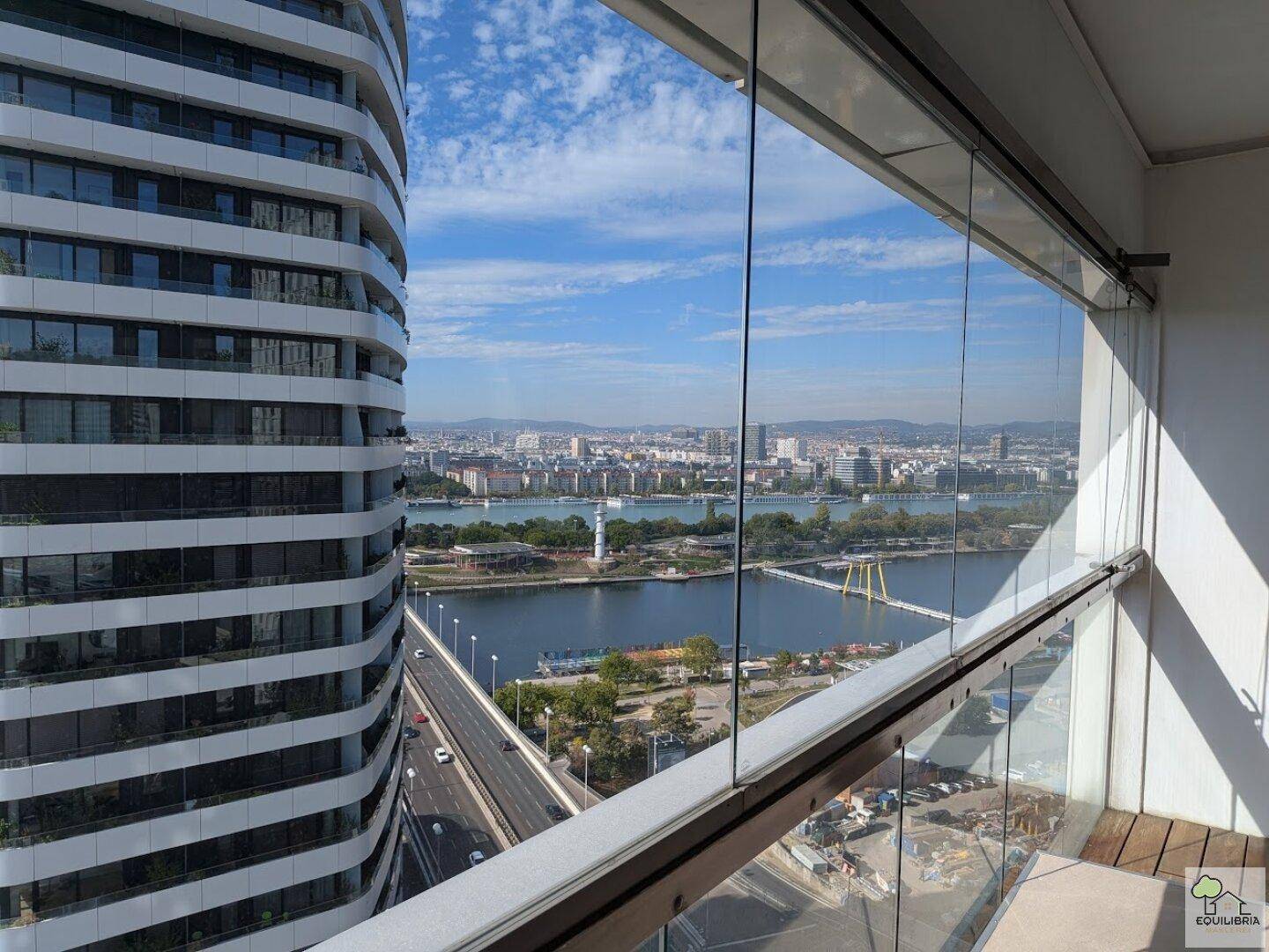 Verglaster Balkon mit Holzboden und weitem Blick über die Stadt und den Fluss.