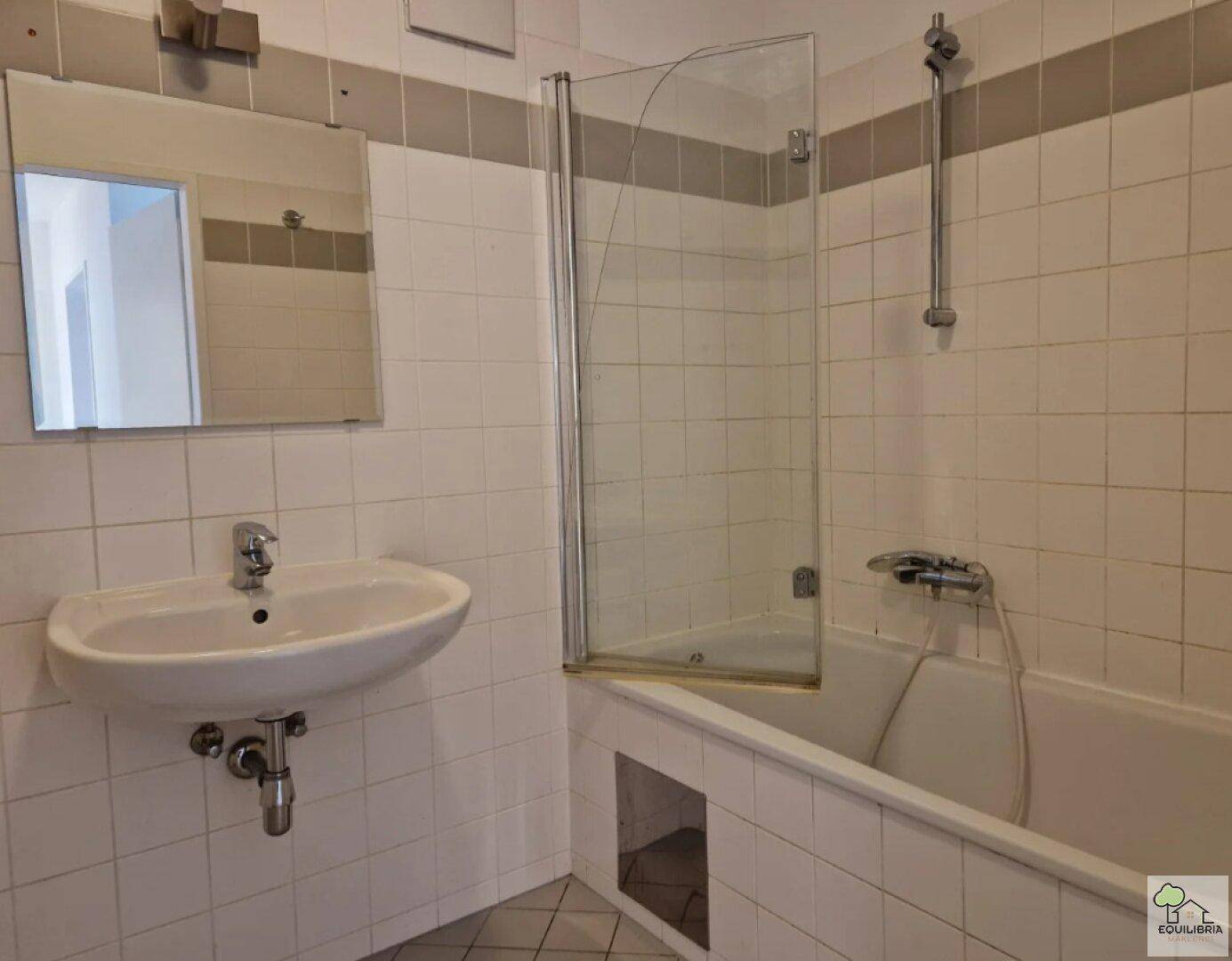 Badezimmer mit Badewanne, Duschabtrennung und weiß gefliesten Wänden.