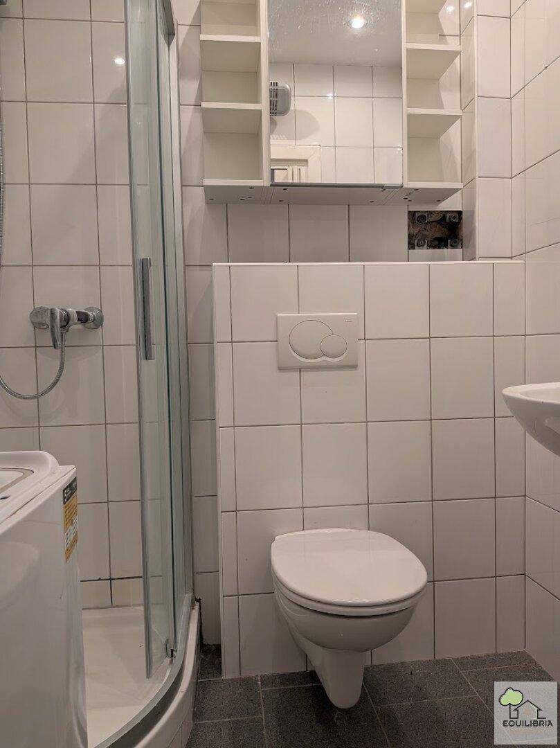 Modern gefliestes Badezimmer mit Dusche, wandhängendem WC und Spiegelschrank.