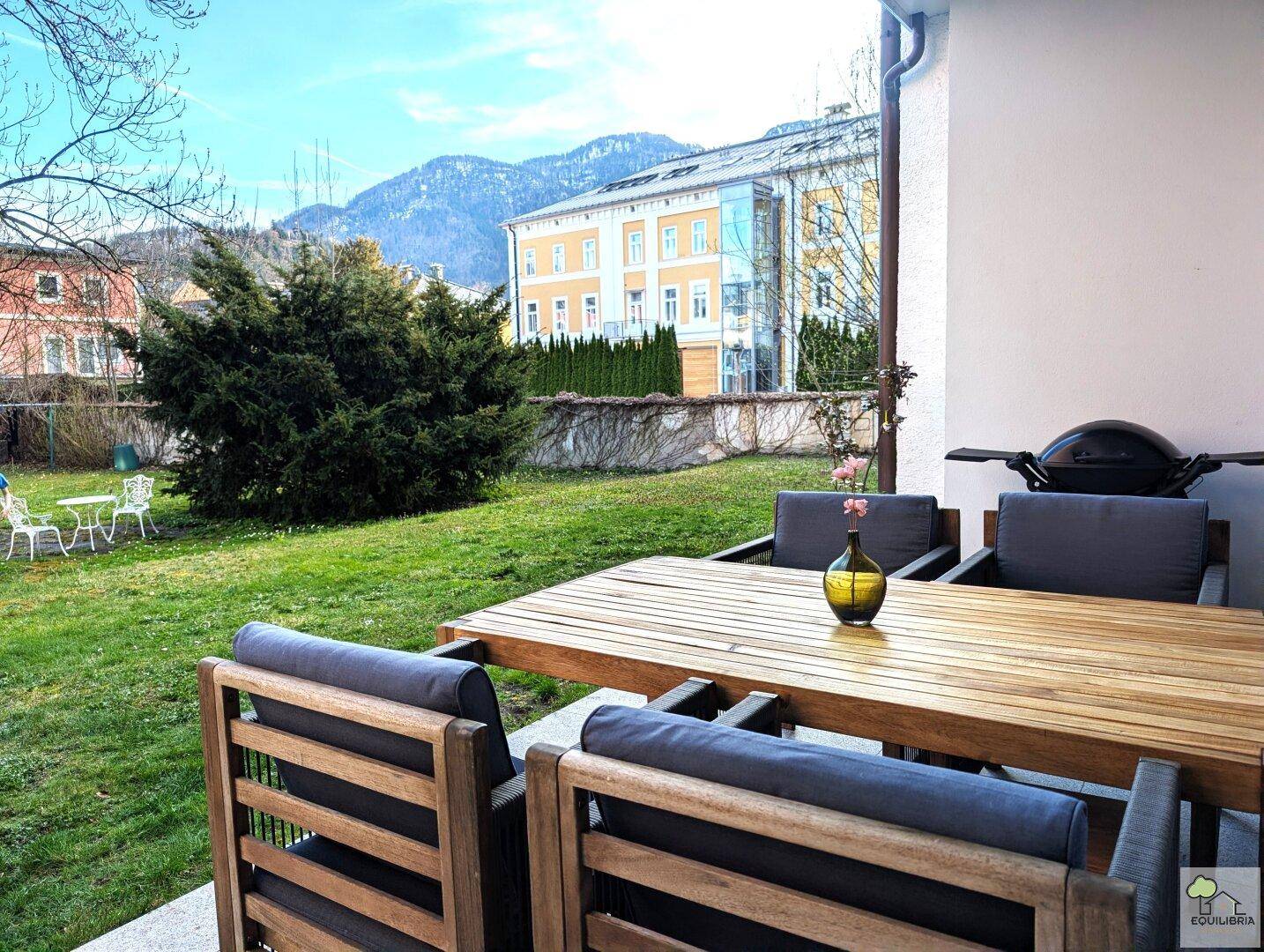 Gemütliche Terrasse mit Esstisch, Stühlen und Blick auf den Garten und die Berge.
