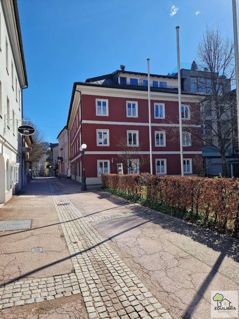 Historisches Gebäude mit roter Fassade an einer ruhigen Stadtstraße.