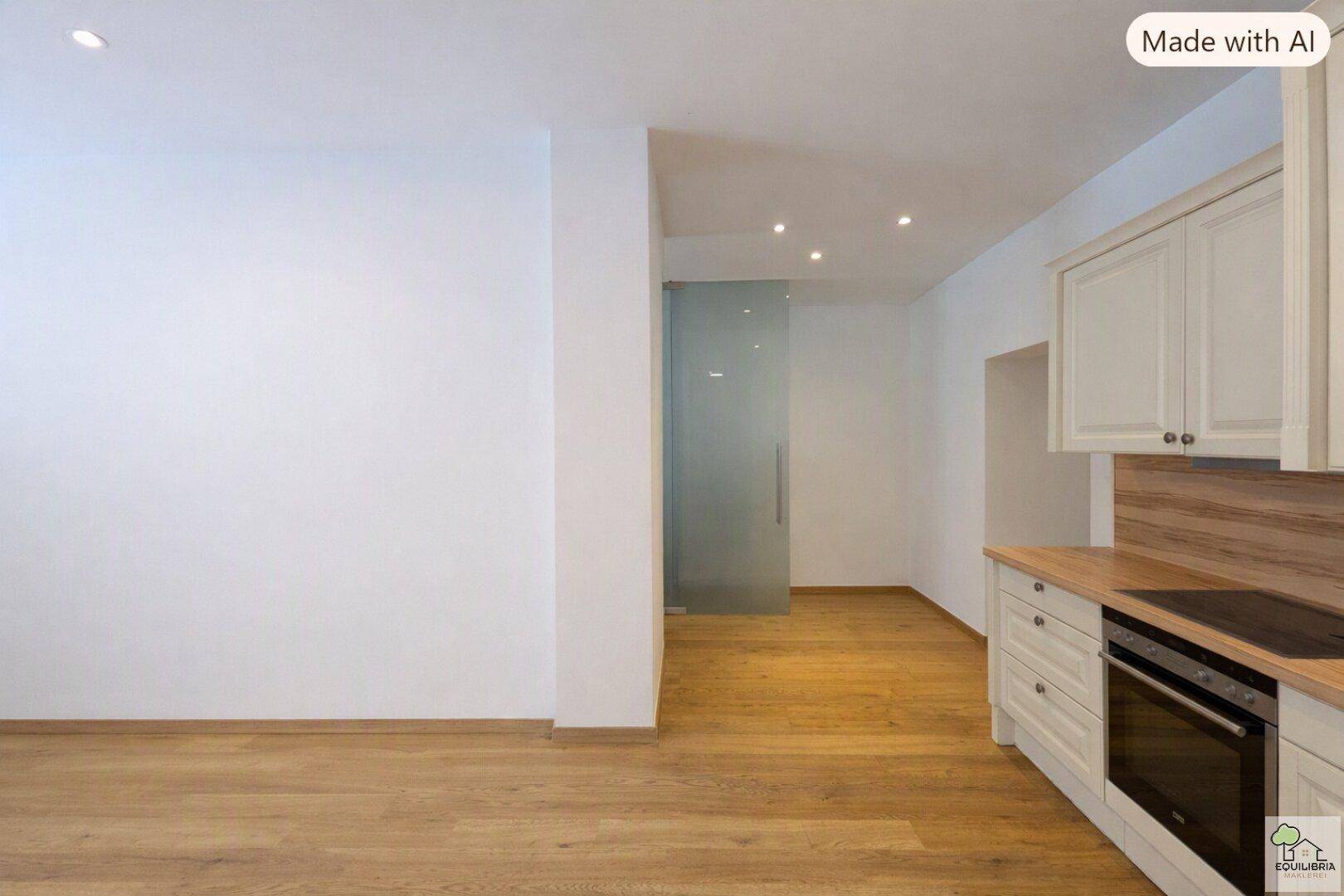 Offener Wohnbereich mit moderner Einbauküche, Holzboden und Glasschiebetür.