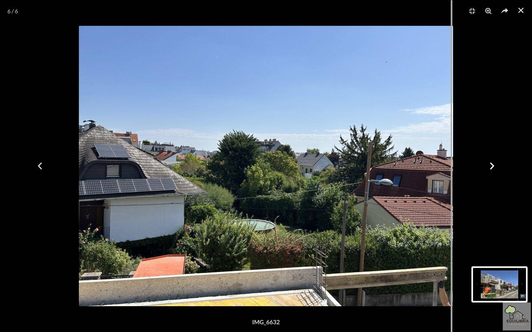 Ausblick von der Baustelle auf umliegende Häuser, viel Grün und Solarpaneele auf einem Dach.