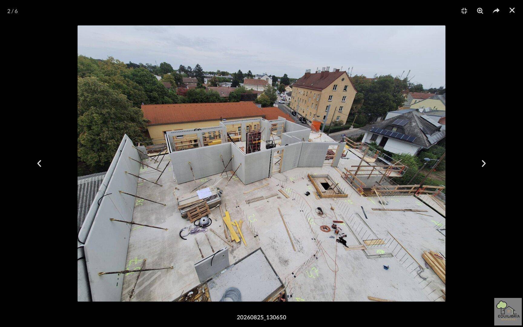 Luftaufnahme einer Baustelle mit Betonbodenplatte und umliegenden Gebäuden in städtischer Umgebung.