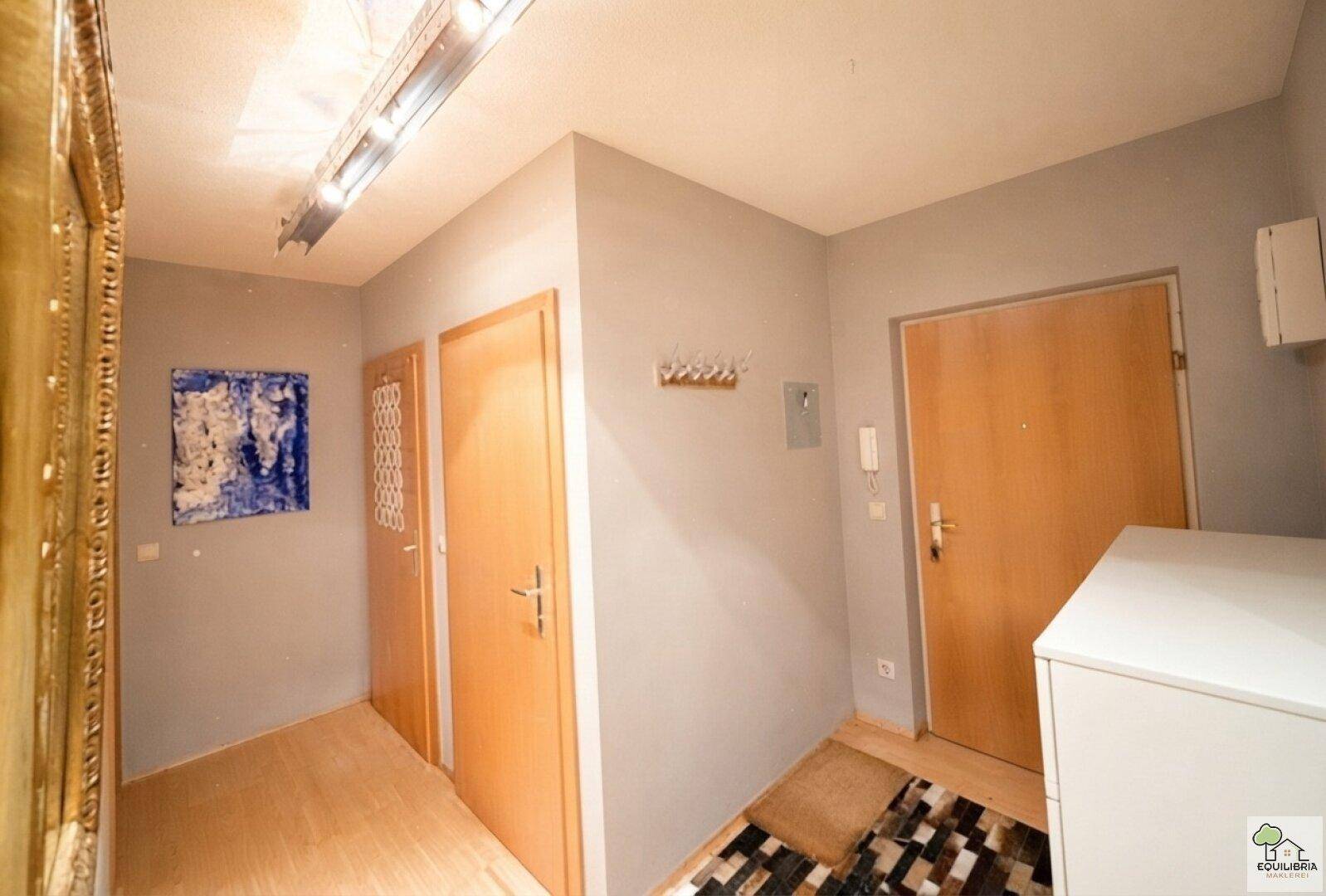 Heller Flur mit Holzboden, mehreren Türen und einer modernen Wandgestaltung.