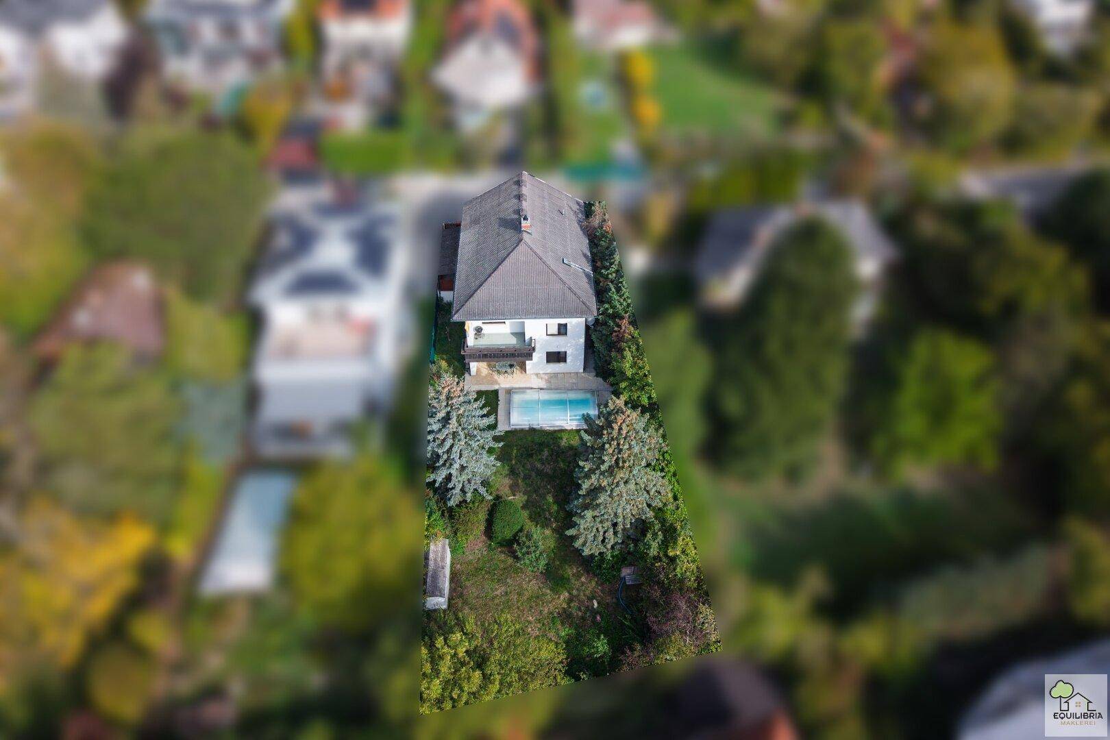 Luftaufnahme des Anwesens mit Haus, Garten und Pool in einer grünen Wohngegend.