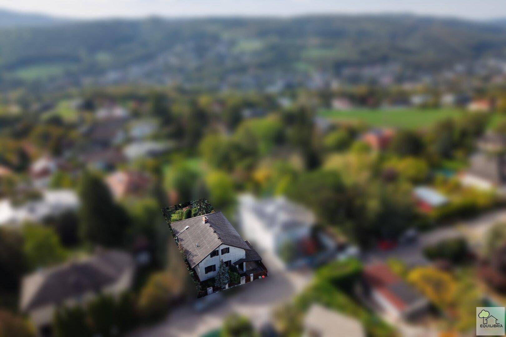 Weitläufige Luftaufnahme des Hauses und der umliegenden grünen Landschaft mit weiteren Gebäuden.