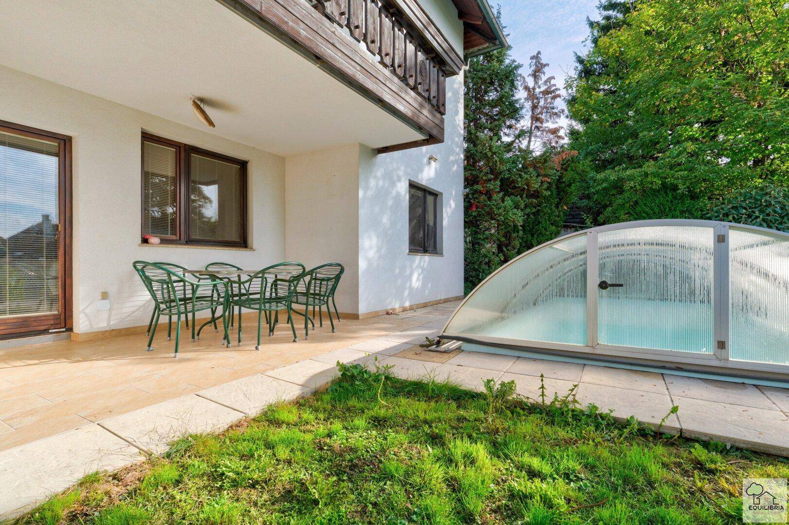 Gemütliche Terrasse mit Gartenmöbeln und einem überdachten Poolbereich im Freien.