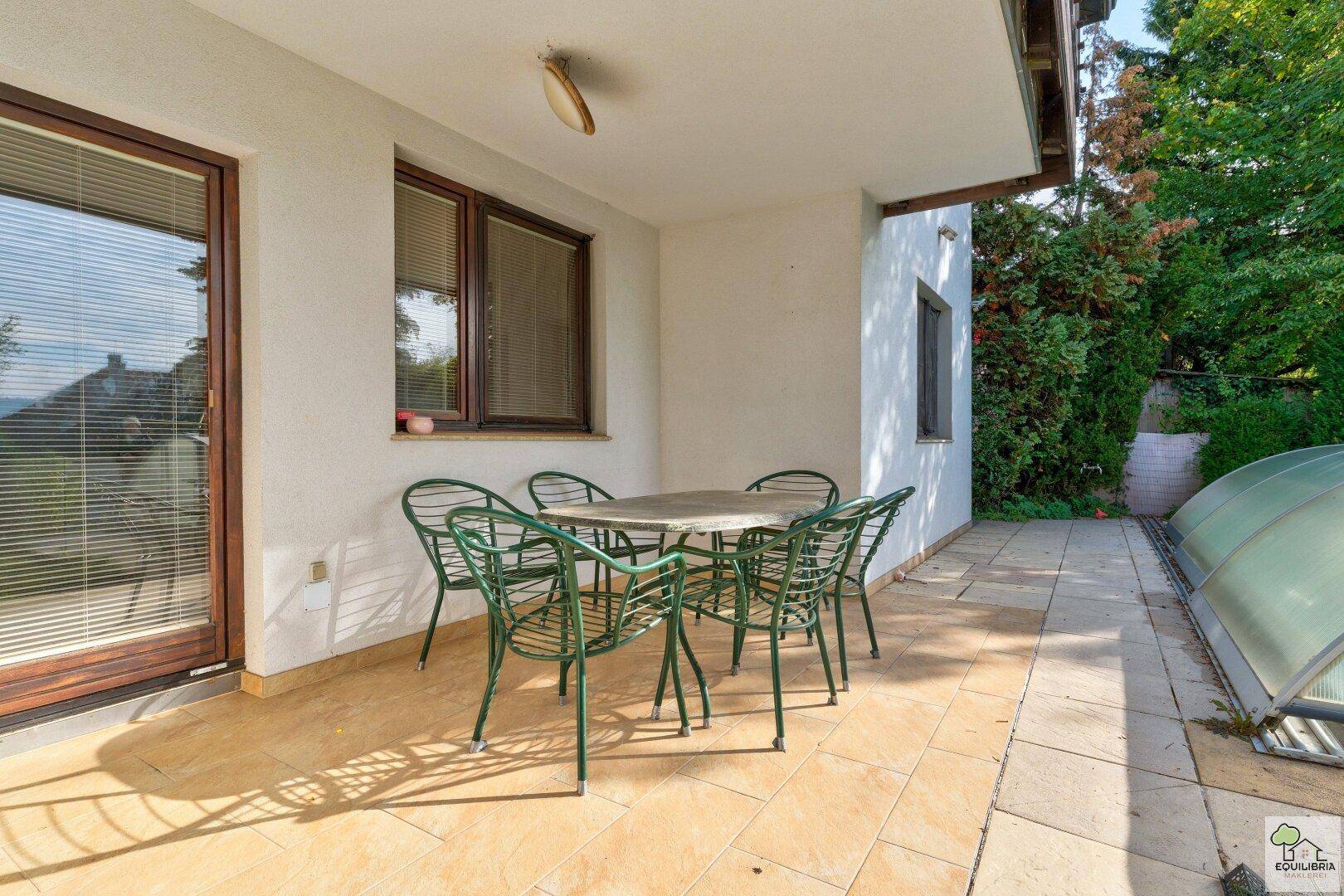 Detailansicht der gefliesten Terrasse mit Gartenmöbeln und Zugang zum Haus.