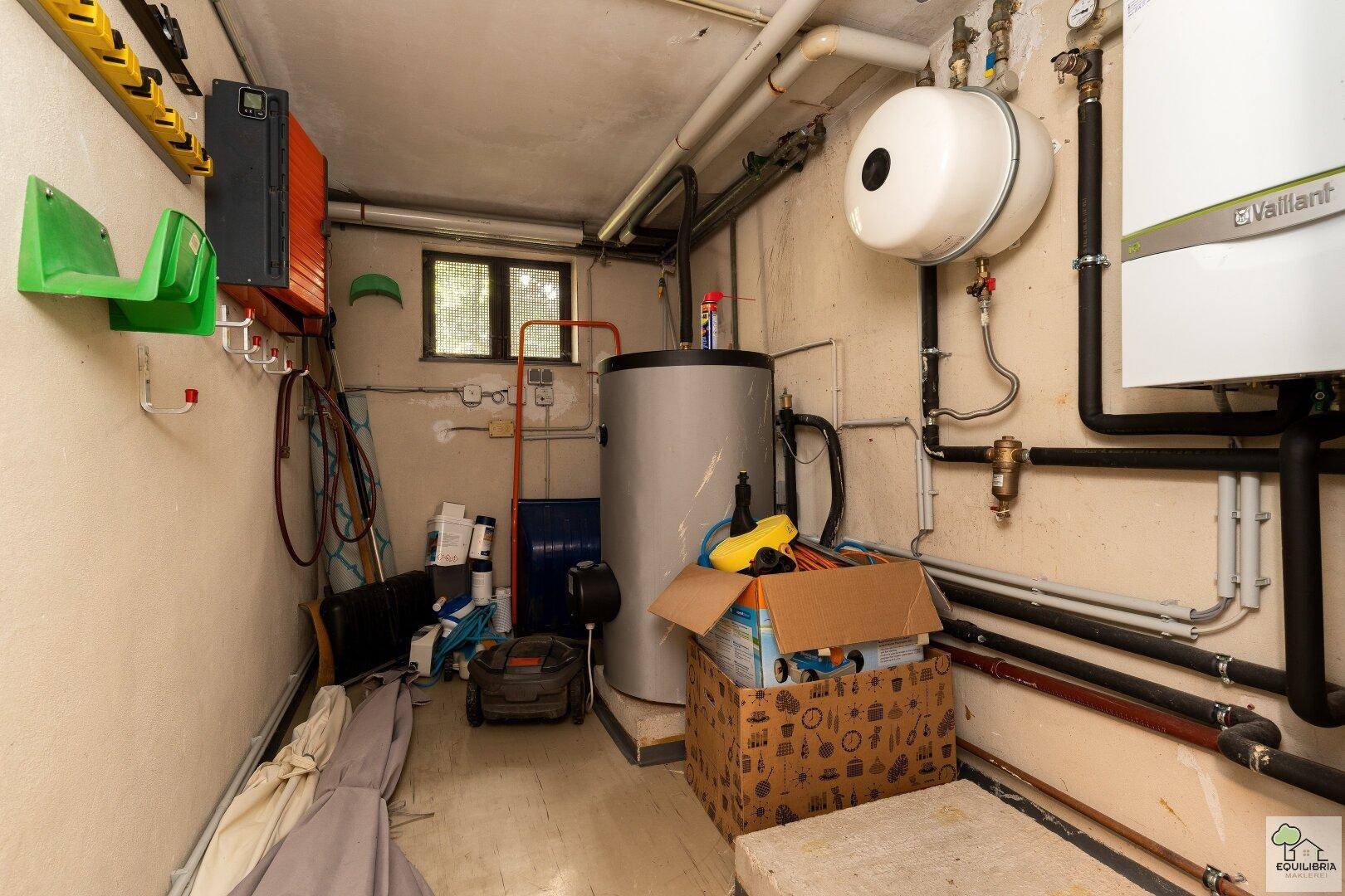 Heizungsraum mit Warmwasserspeicher, Heizungsanlage und sichtbaren Installationen.