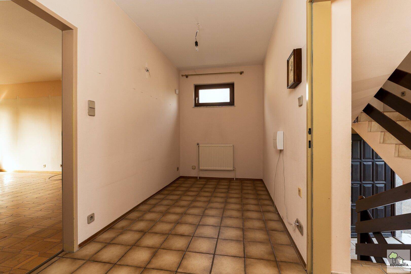 Eingangsbereich mit Fliesenboden und Zugang zum Treppenhaus, hell beleuchtet.