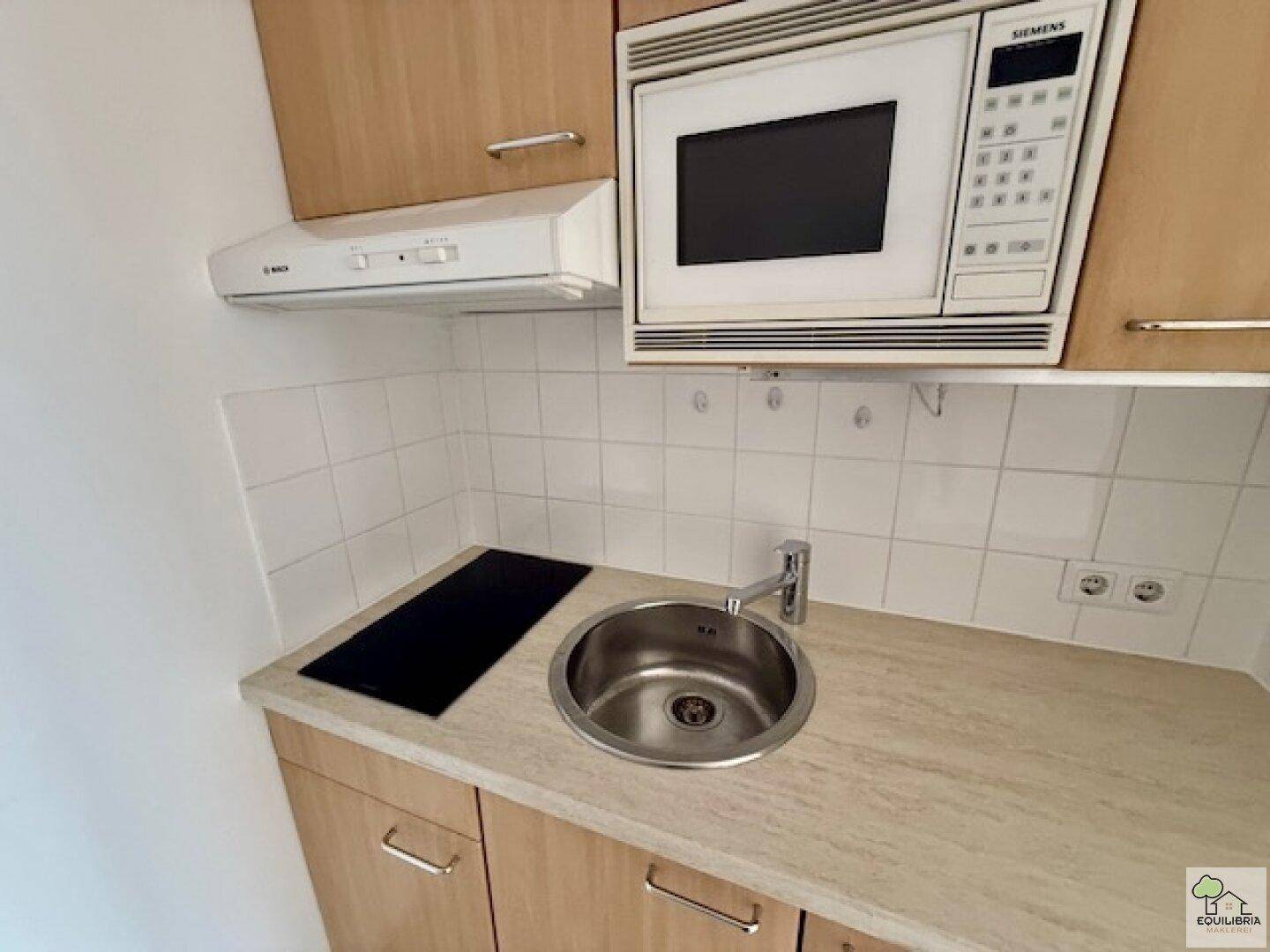 Detaillierte Ansicht der Küchenzeile mit Spüle, Kochfeld und Siemens Mikrowelle.