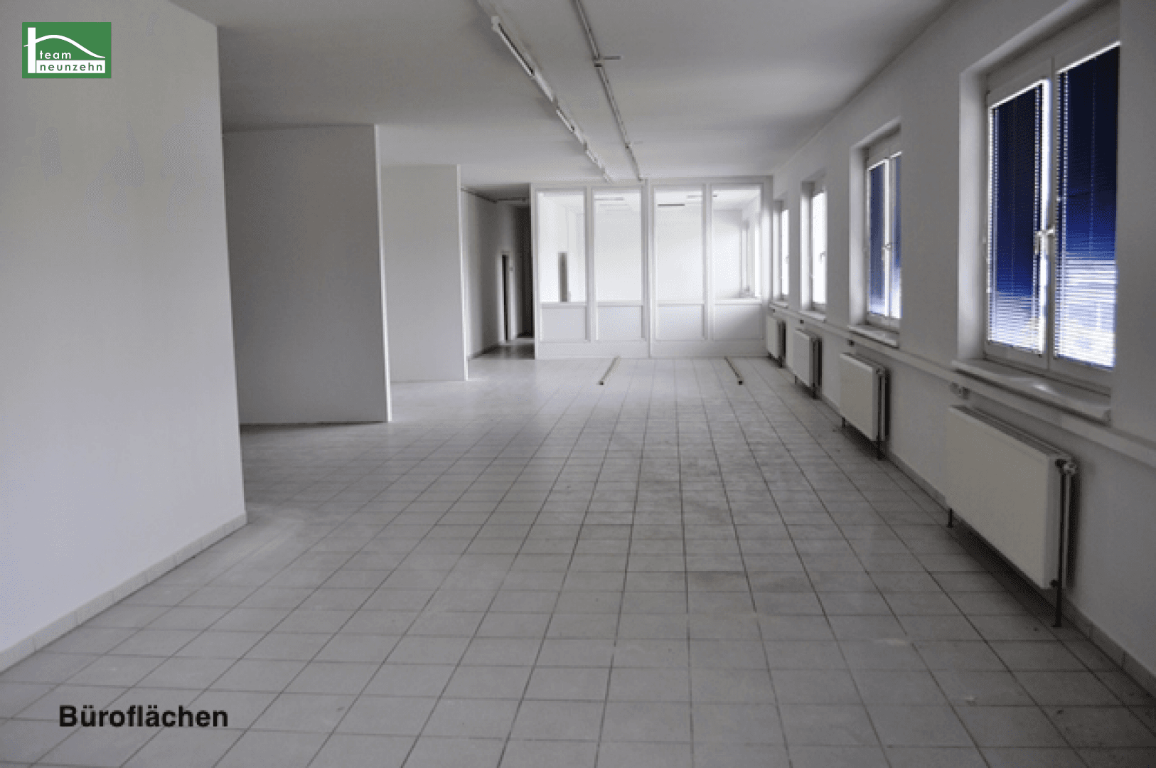 Geräumiger, leerer Bürobereich mit Fliesenboden und mehreren Fenstern für viel Tageslicht.
