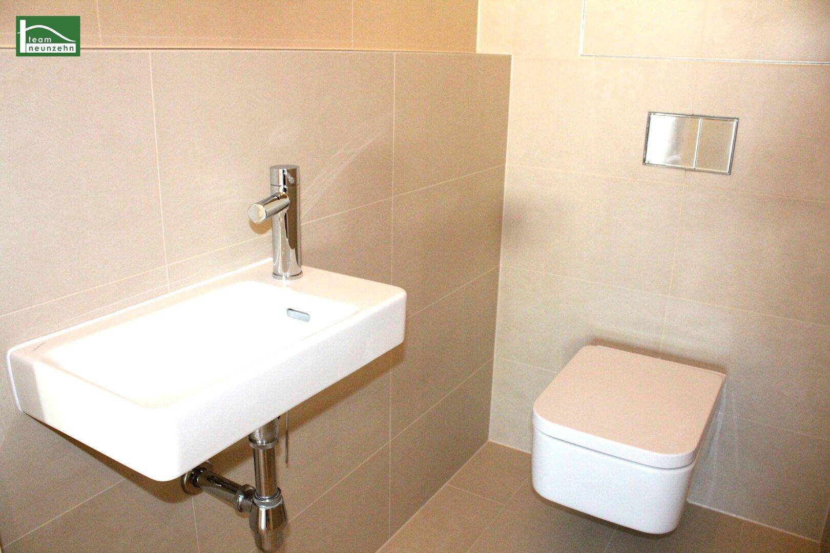 Separates Gäste-WC mit wandhängender Toilette und kleinem Waschbecken.