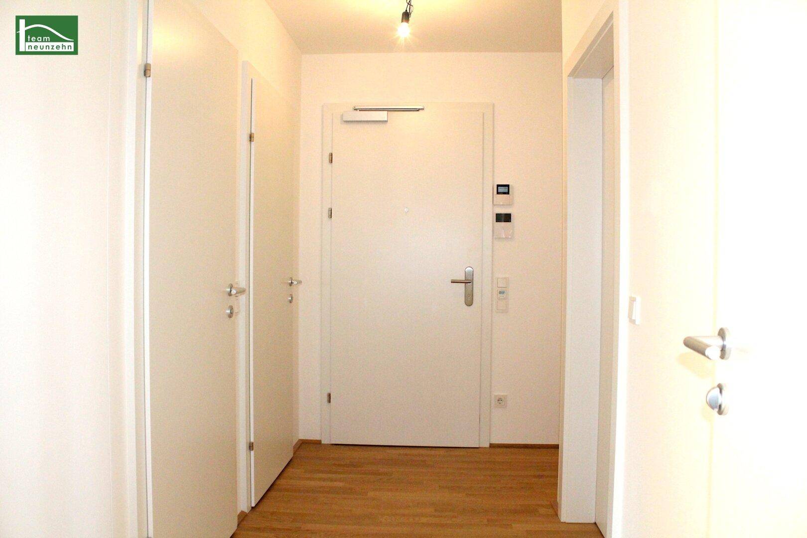 Heller Eingangsbereich mit Holzfußboden und mehreren weißen Türen.