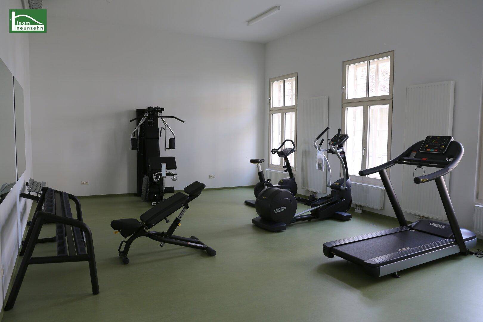 Gemeinschaftlicher Fitnessraum mit Laufband, Fahrrad und Hantelbank für Bewohner.