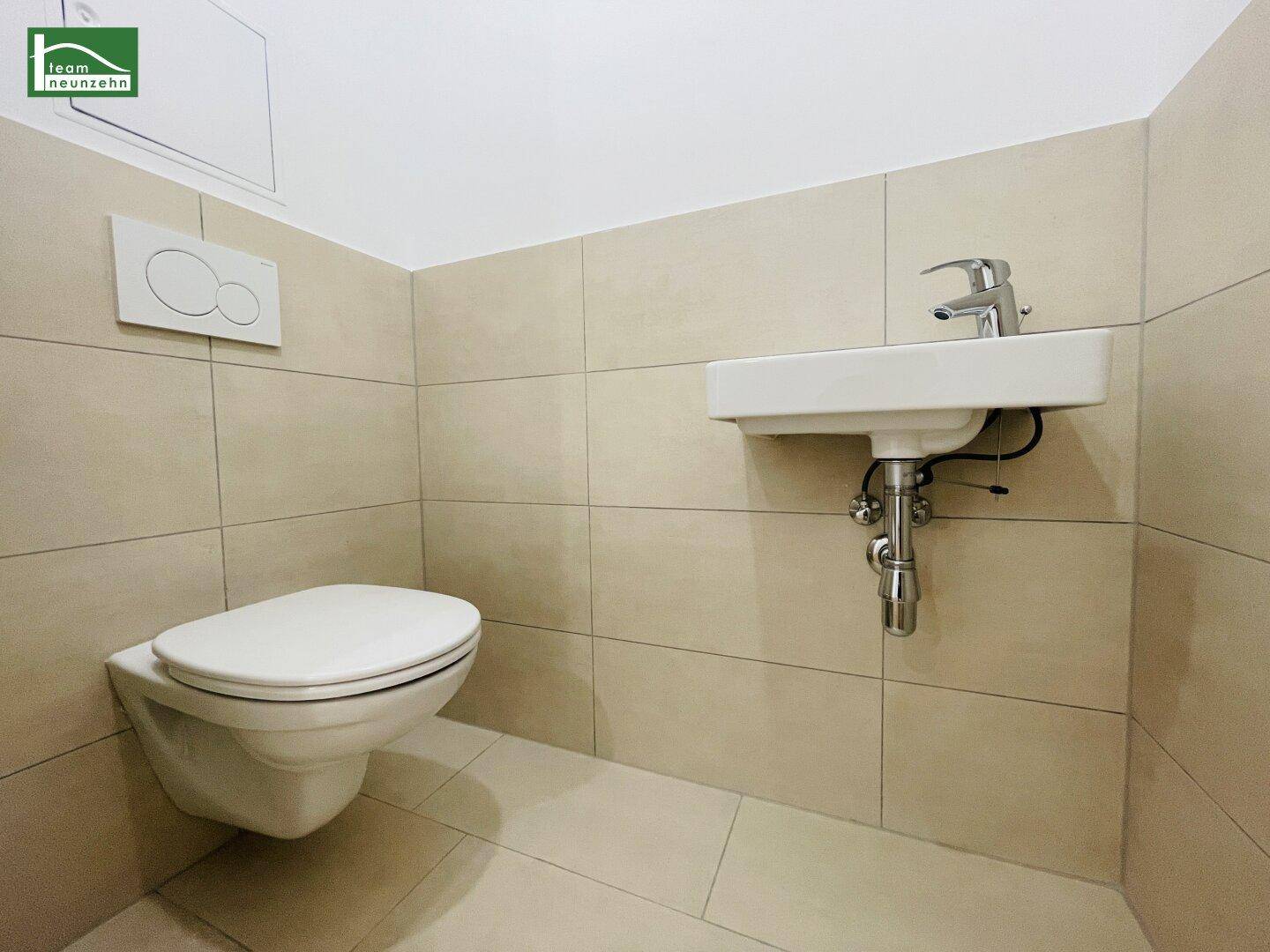 Separates Gäste-WC mit wandhängender Toilette und kleinem Waschbecken.