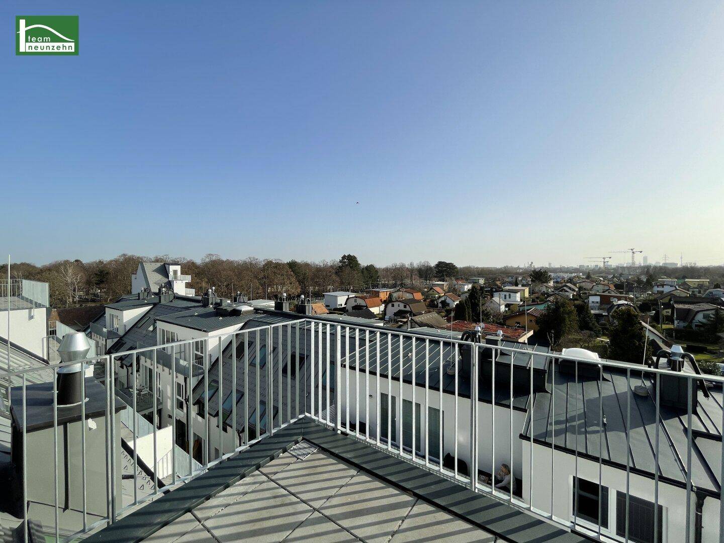 Geräumiger Balkon mit Metallgeländer und Blick über die umliegenden Dächer der Stadt.