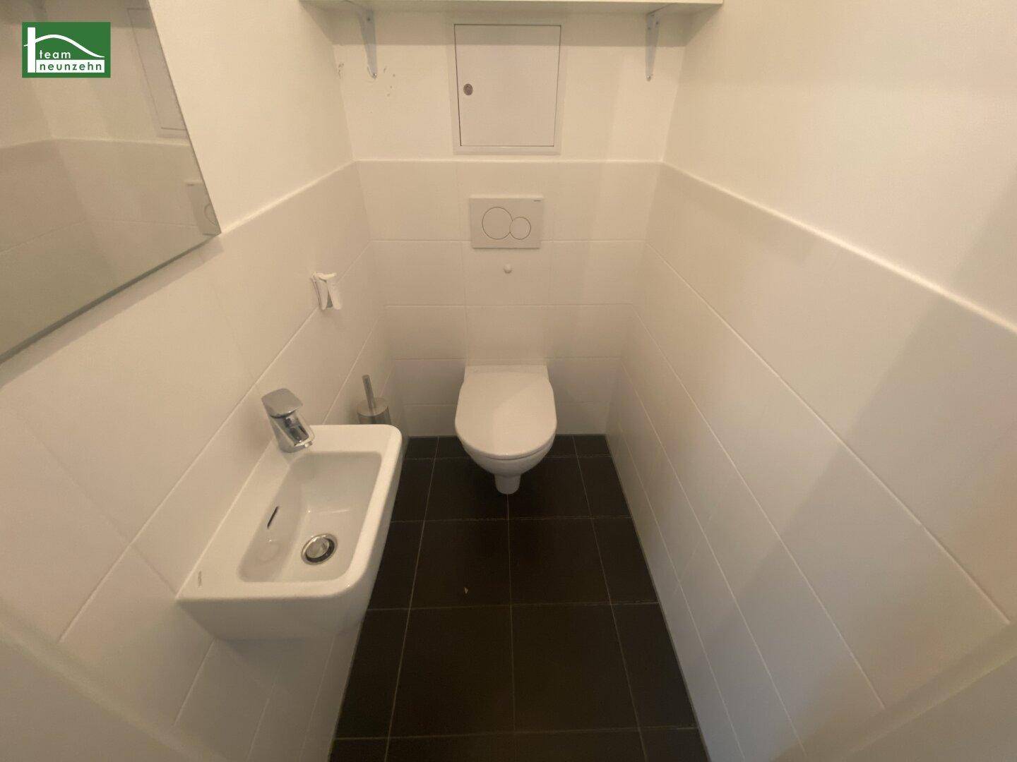 Separates Gäste-WC mit wandhängendem WC und kleinem Handwaschbecken.
