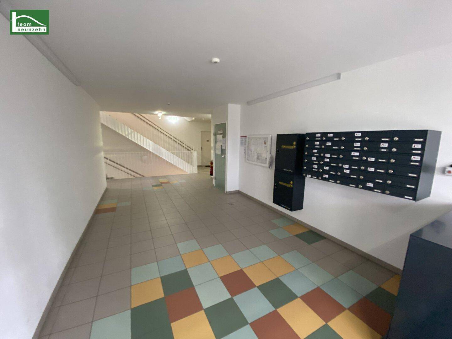 Geräumiger Eingangsbereich mit Briefkästen und einer Treppe im Hintergrund.
