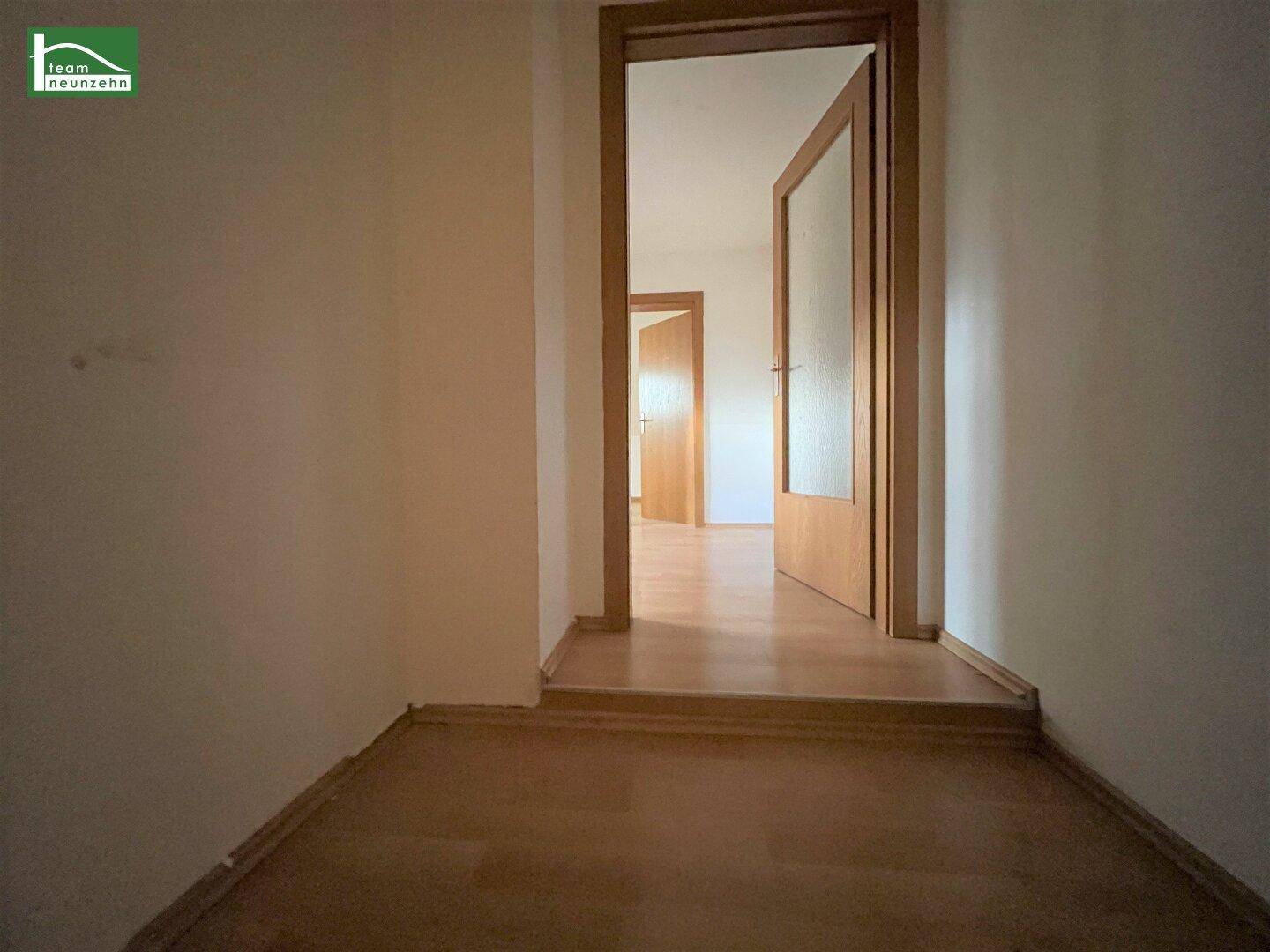 Heller Flur mit Laminatboden, der den Zugang zu mehreren Zimmern der Wohnung ermöglicht.