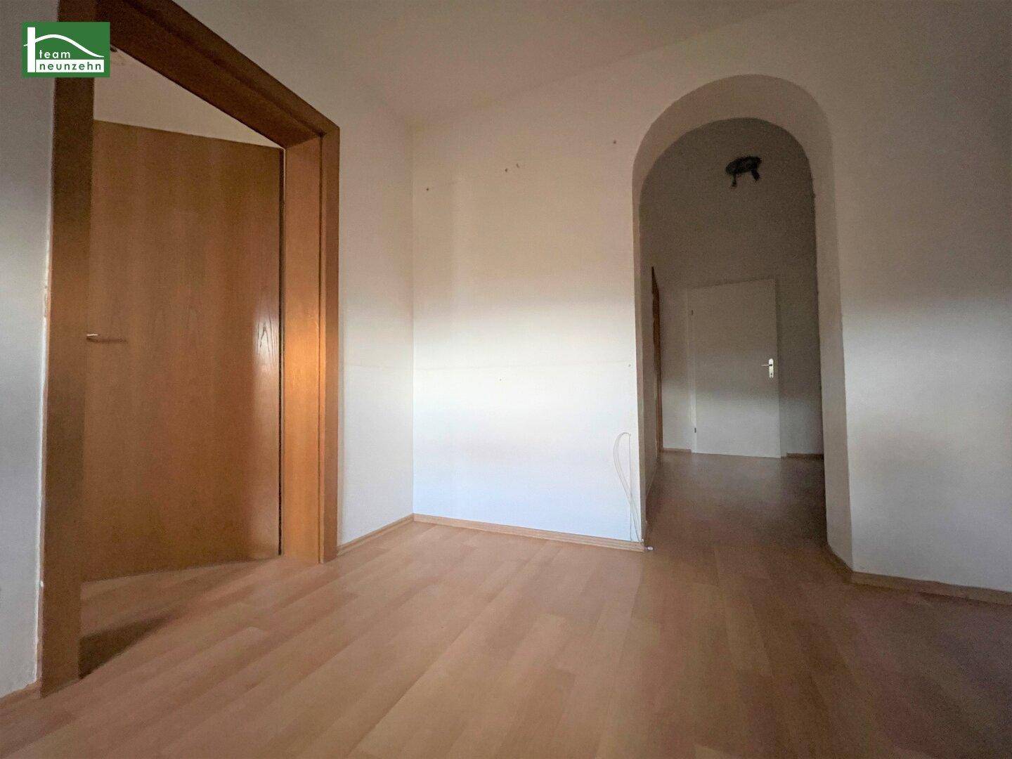 Flur mit Laminatboden und einem eleganten Rundbogen, der zu weiteren Räumen führt.
