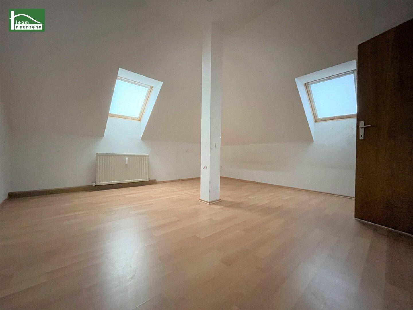 Heller Dachgeschossraum mit zwei Dachfenstern, Laminatboden und schrägen Wänden für vielseitige Nutzung.