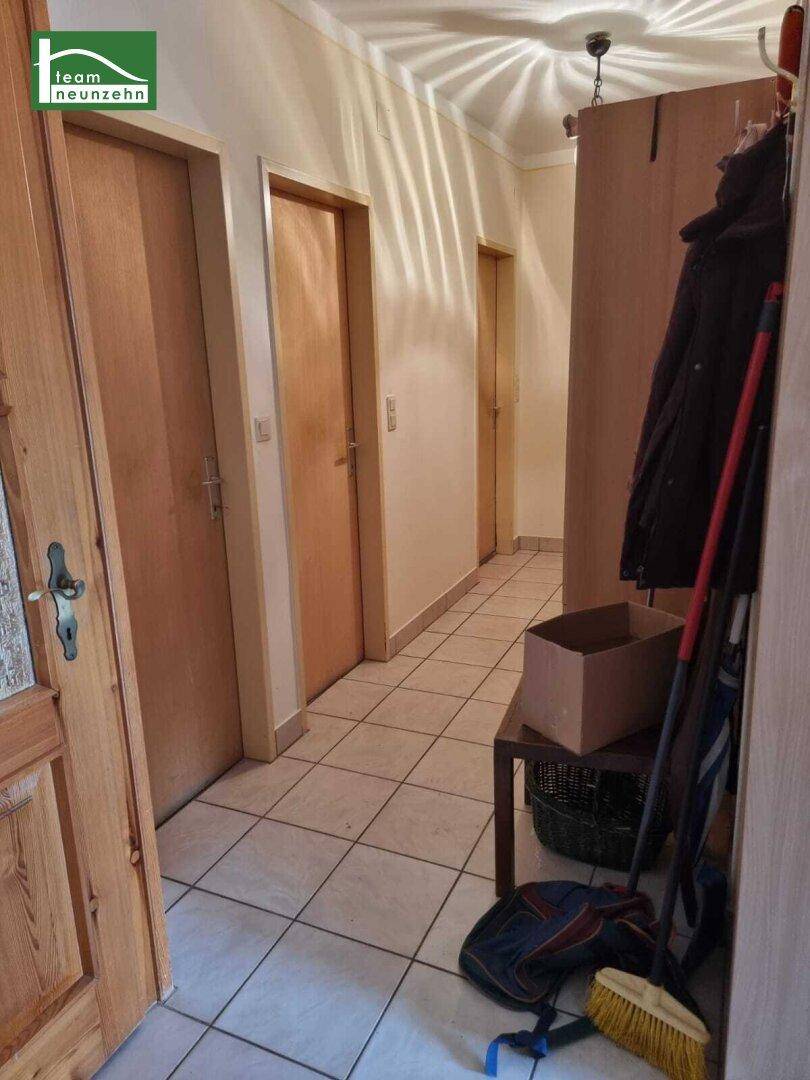 Flur mit Fliesenboden und Holztüren, der zu verschiedenen Räumen führt.