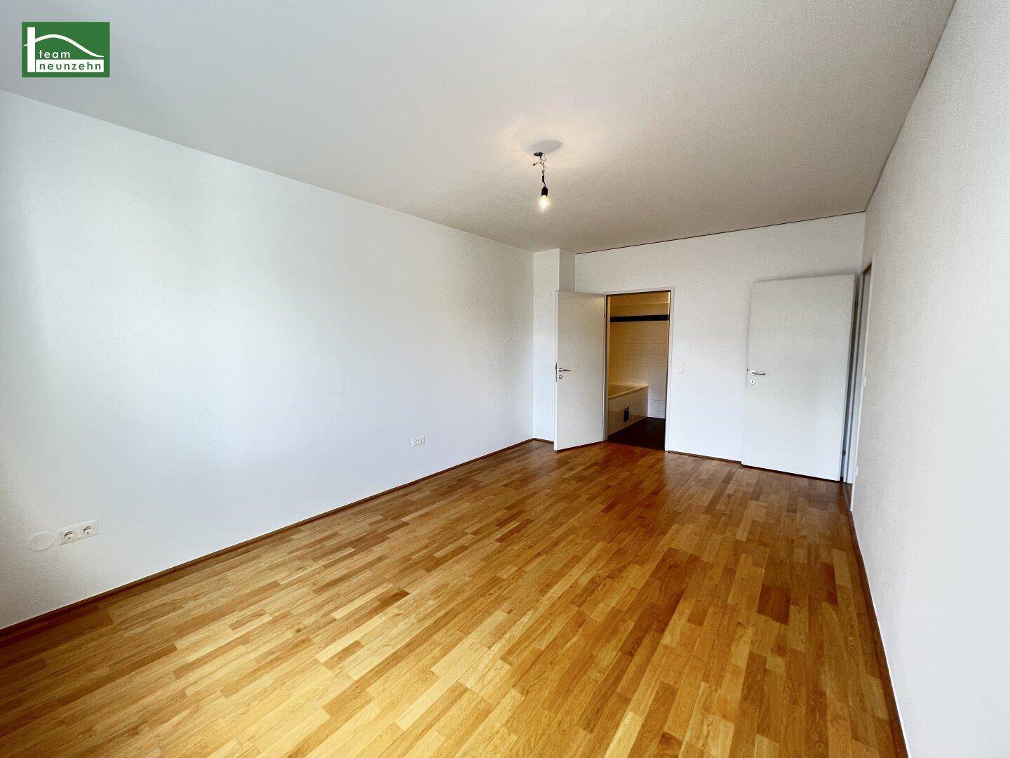 Leeres Zimmer mit hellem Parkettboden und weiß gestrichenen Wänden, bereit zur individuellen Gestaltung.