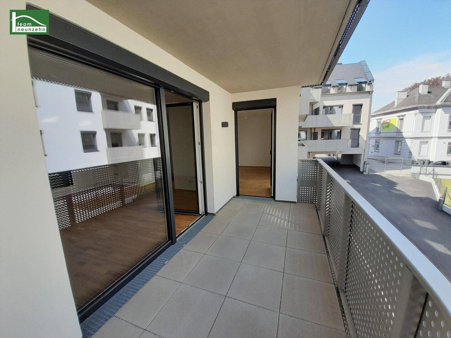 Geräumiger Balkon mit Fliesenboden und Blick auf die umliegenden Gebäude.