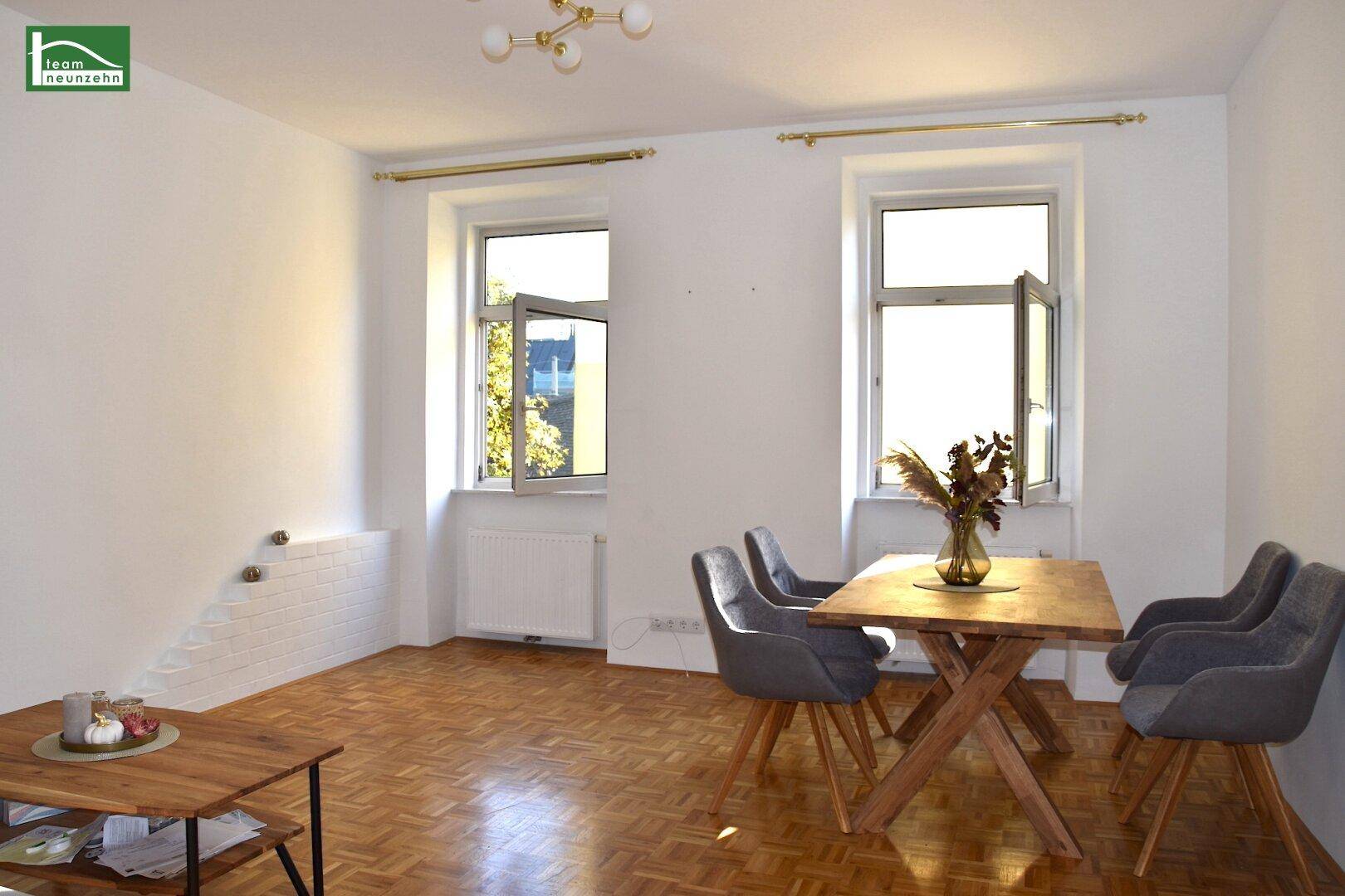 Geräumiger Wohn- und Essbereich mit Parkettboden, viel Tageslicht und moderner Einrichtung.