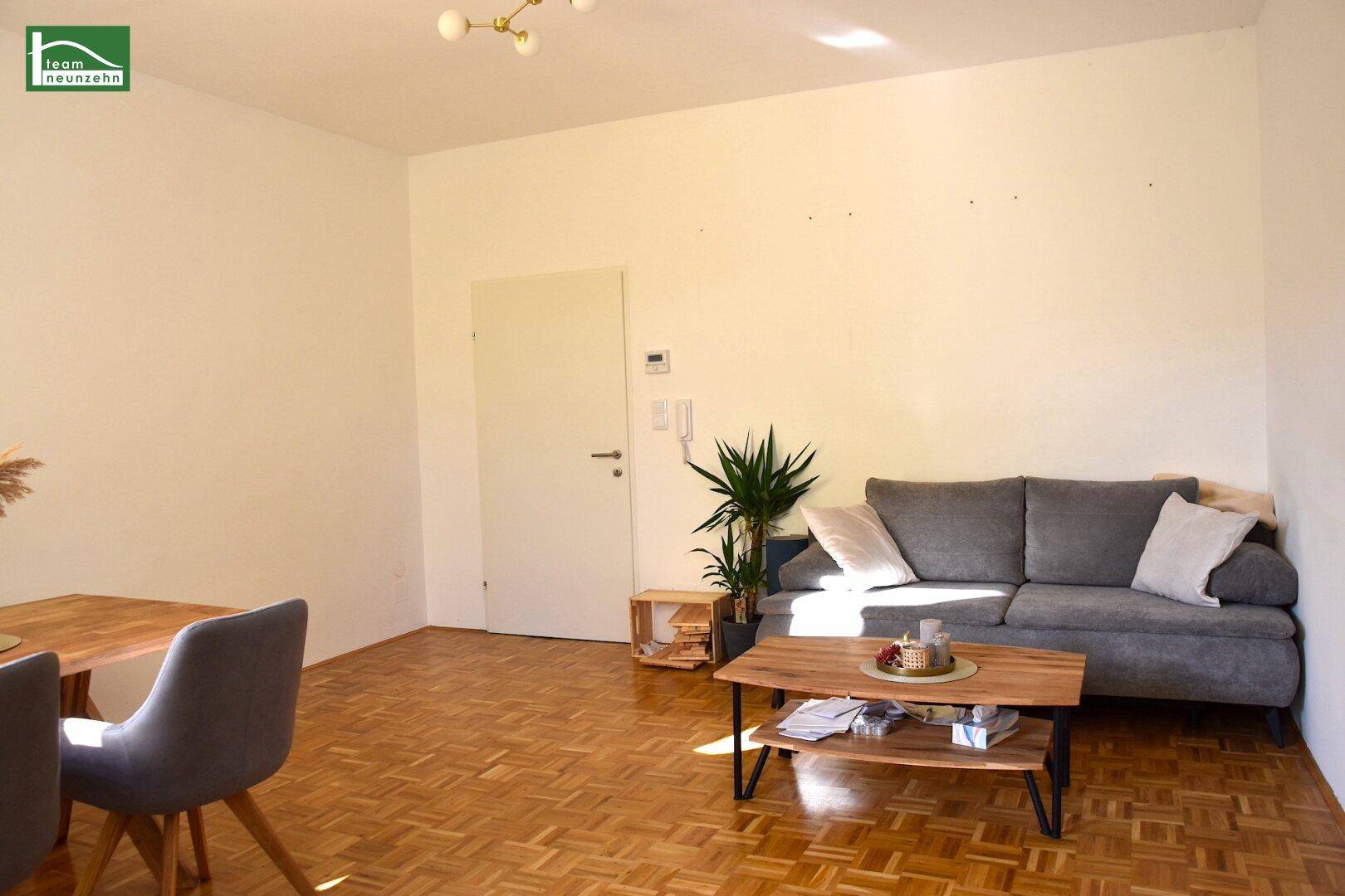 Gemütlicher Wohnbereich mit grauem Sofa, Couchtisch und Parkettboden, ideal zum Entspannen.