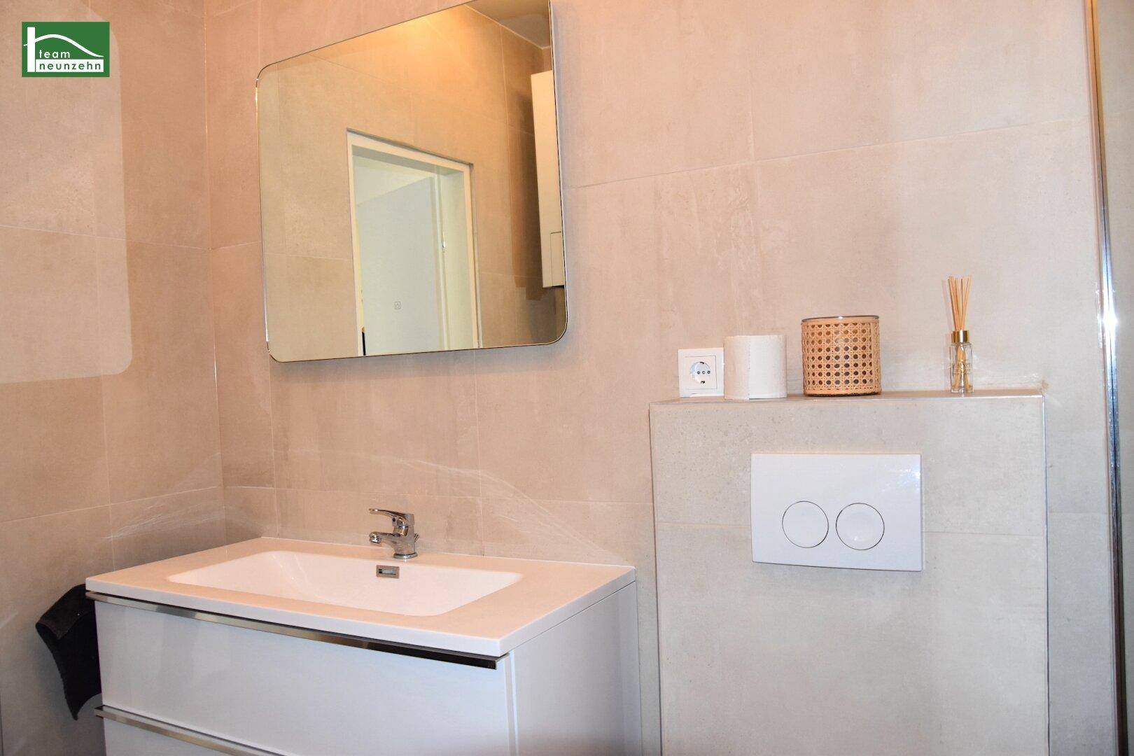 Elegantes Badezimmer mit modernem Waschtisch, großem Spiegel und stilvollen Armaturen.