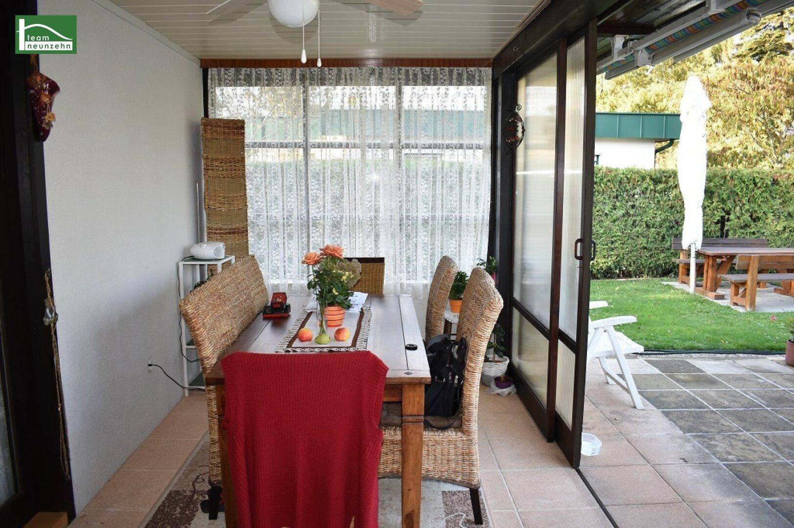Heller Wintergarten als Essbereich mit Korbmöbeln und direktem Zugang zur Terrasse und Garten.