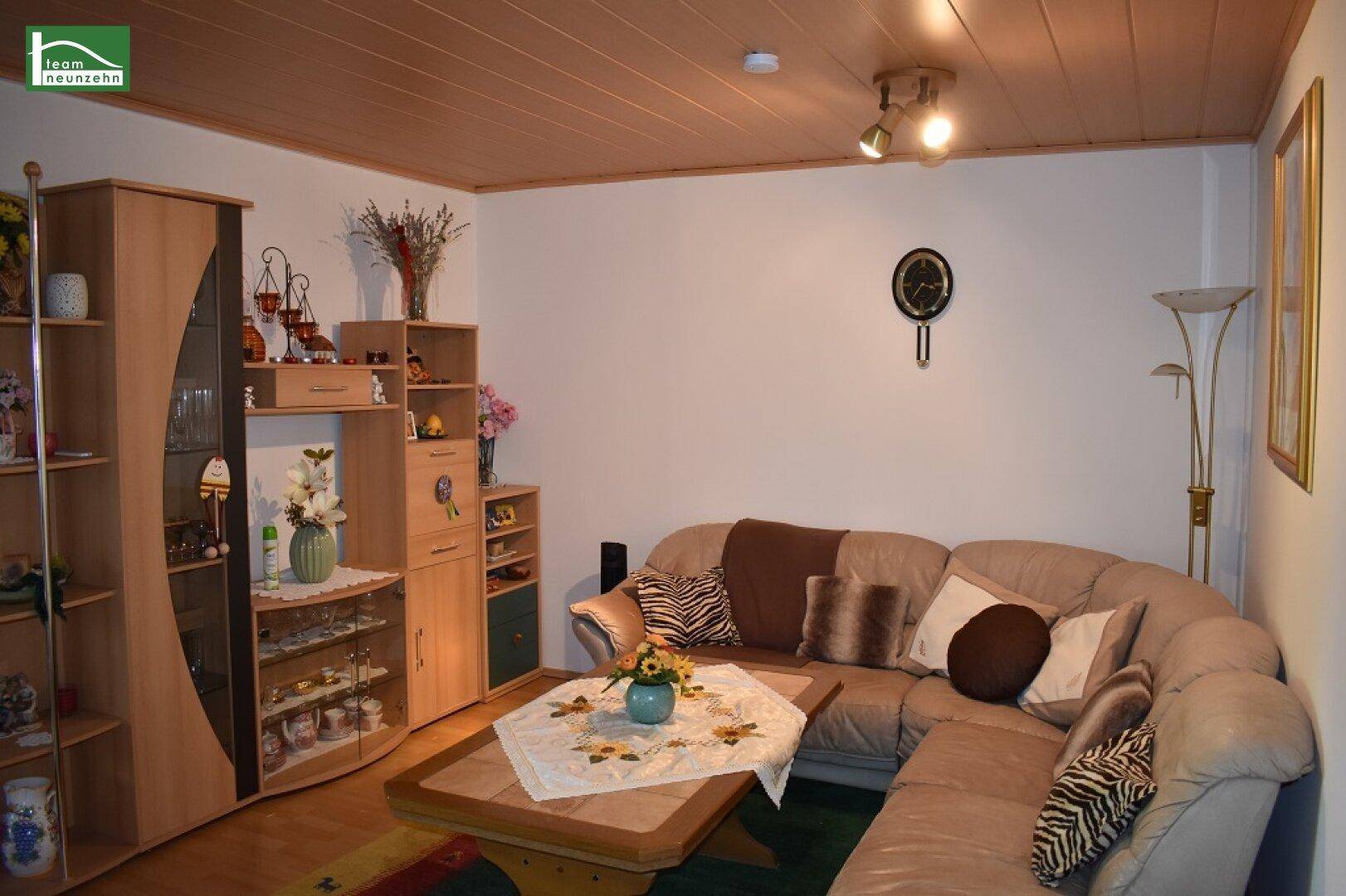 Gemütliches Wohnzimmer mit großem Ecksofa, Holzdecke und traditioneller Einrichtung.