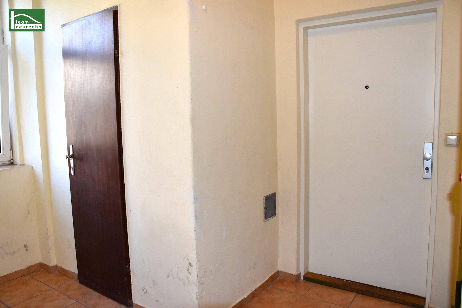 Heller Flur mit Fliesenboden und zwei Türen, der den Eingangsbereich der Wohnung zeigt.