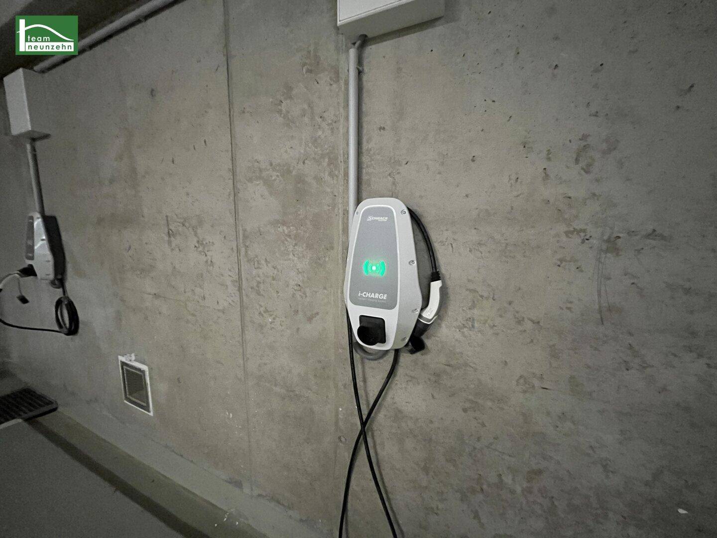 Nahaufnahme einer modernen Ladestation für Elektrofahrzeuge in einer Tiefgarage mit Betonwänden.