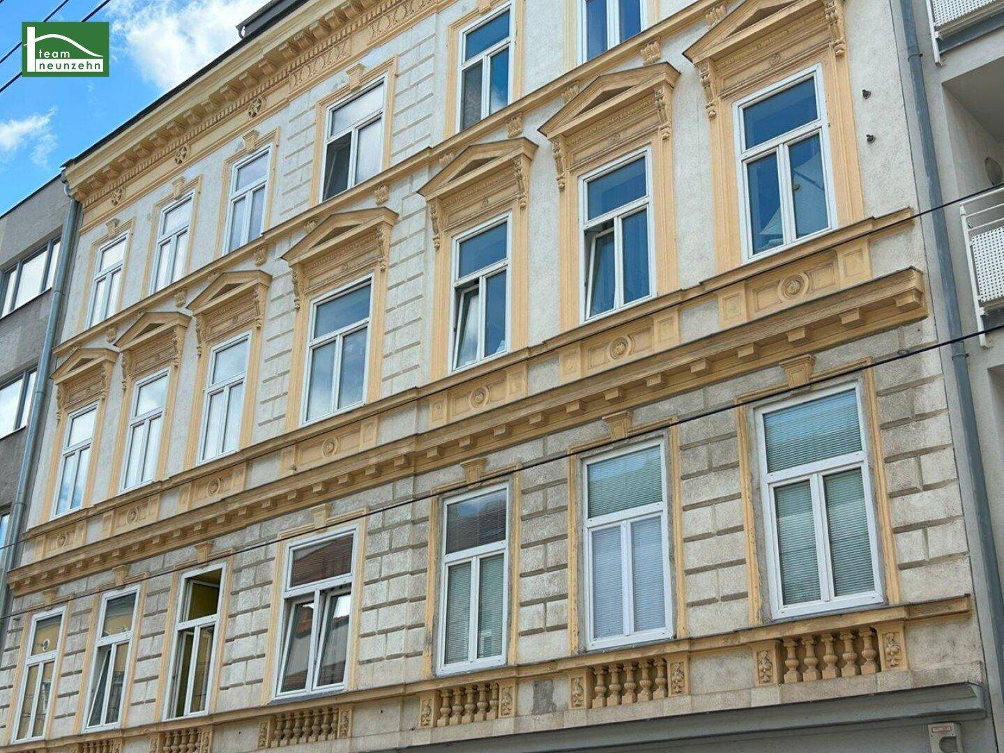 Detailansicht einer historischen Gebäudefassade mit reich verzierten Fenstern und Stuckelementen.