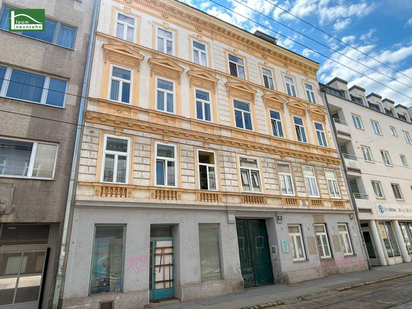 Historische Gebäudefassade mit vielen Fenstern und einer grünen Eingangstür, die das Straßenbild prägt.