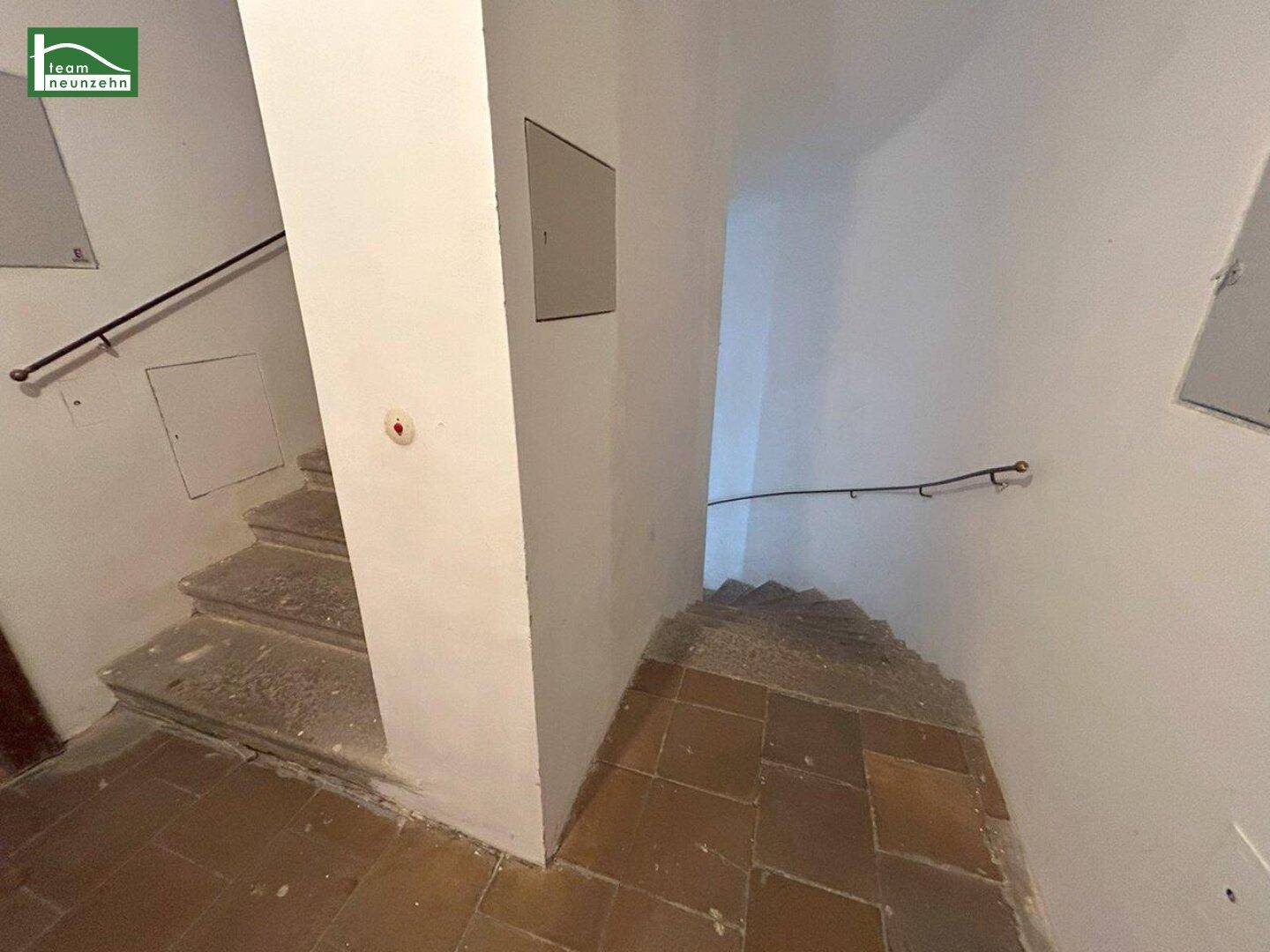 Treppenhaus mit Steinstufen und einem einfachen Handlauf, der in die oberen Stockwerke führt.