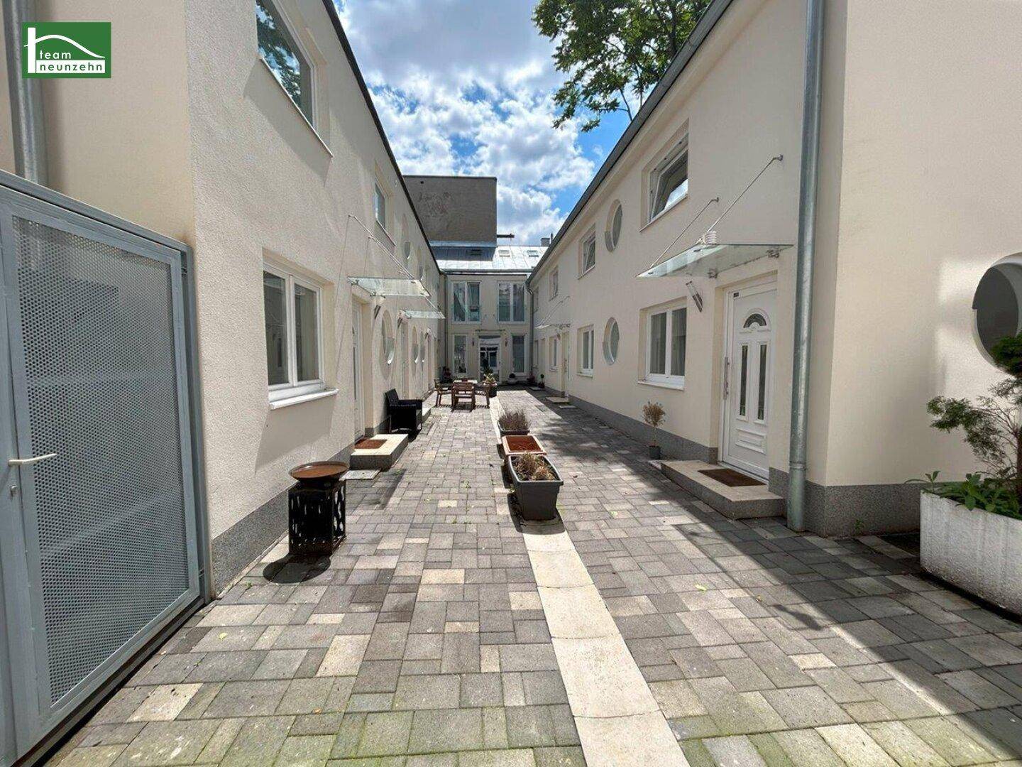 Gepflasterter Innenhof mit Sitzgelegenheiten und modernen Gebäudefassaden, die eine ruhige Atmosphäre schaffen.